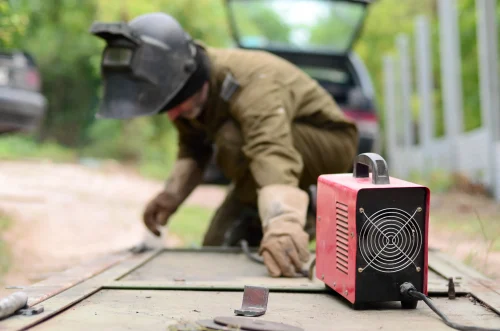 2026 08 10T16 25 56.239255Z old man welder in brown uniform welding mask and welders leathers weld metal door with arc welding machine outdoors photo 1