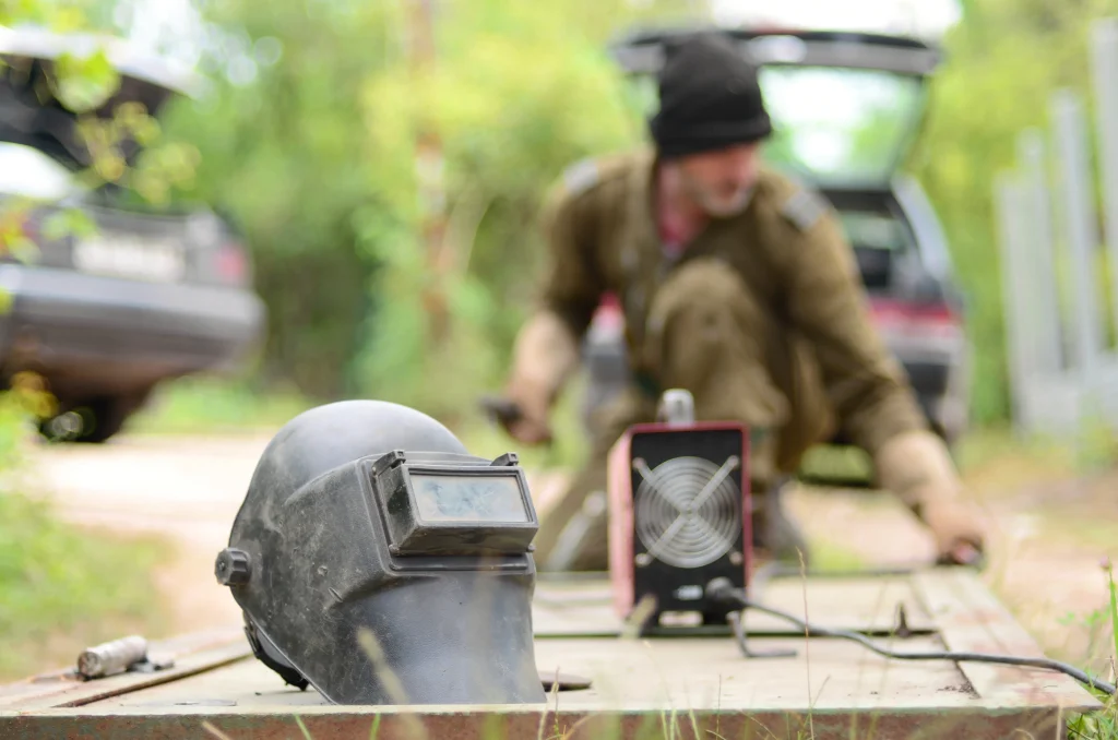 2026 08 10T16 25 56.239561Z old man welder in brown uniform prepares metal door surface for welding with arc welding machine outdoors photo 1